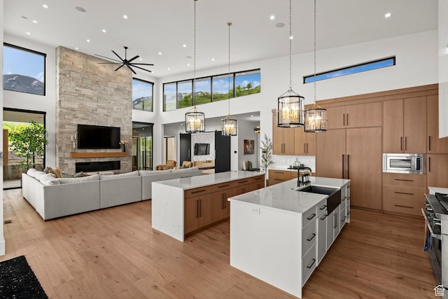 kitchen with a spacious island, a towering ceiling, appliances with stainless steel finishes, a sink, and open floor plan