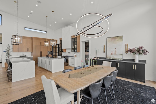 dining room featuring high vaulted ceiling, a chandelier, and light wood-type flooring