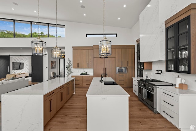 kitchen with a spacious island, appliances with stainless steel finishes, a chandelier, a towering ceiling, and a sink
