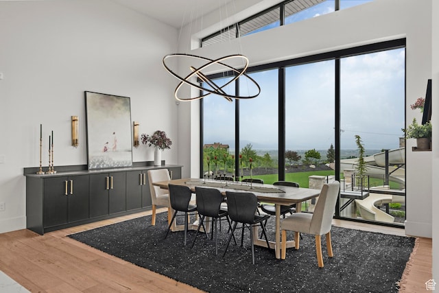 dining space featuring wood finished floors, a chandelier, and a towering ceiling