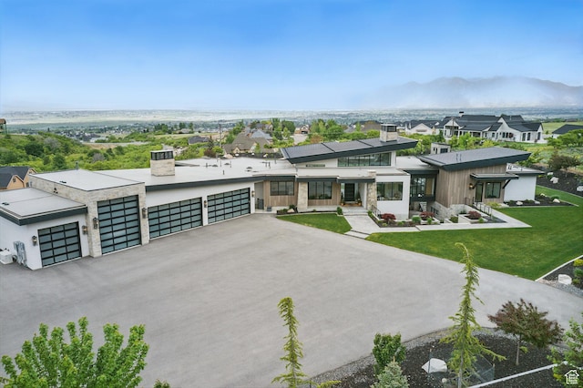 modern home with a chimney, a front lawn, and driveway
