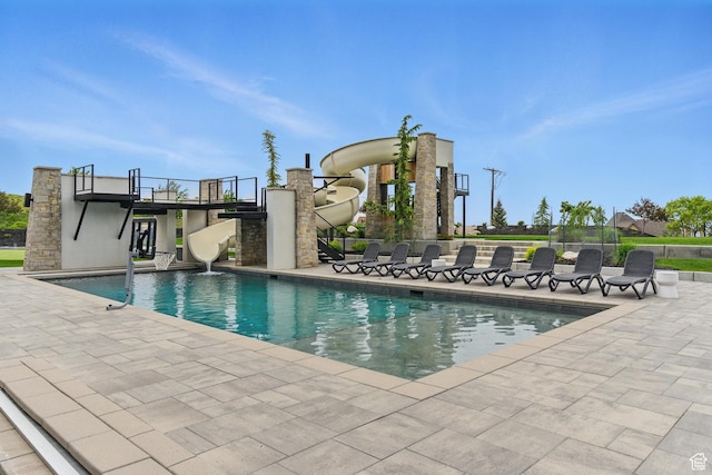 outdoor pool featuring a water slide and a patio