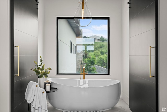bathroom with a soaking tub, marble finish flooring, and a sink