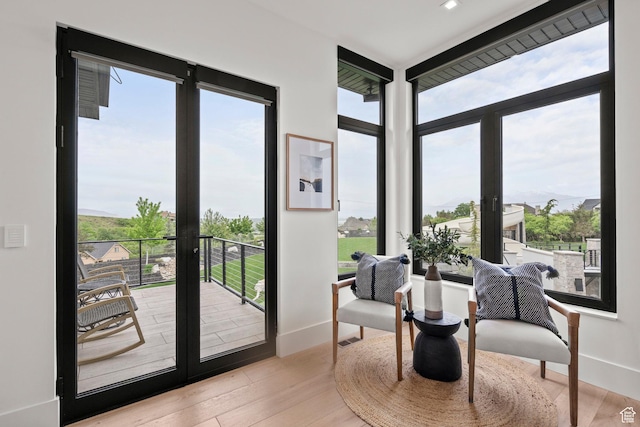 sitting room with french doors, healthy amount of natural light, baseboards, and wood finished floors