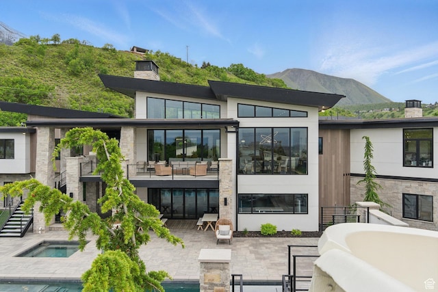 rear view of property featuring a chimney, a mountain view, a patio, an outdoor pool, and an outdoor hangout area
