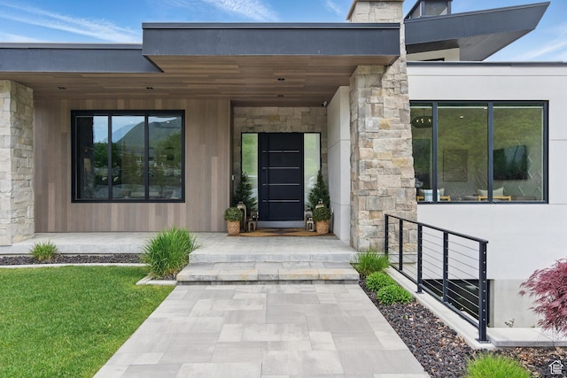 doorway to property featuring stone siding and a lawn