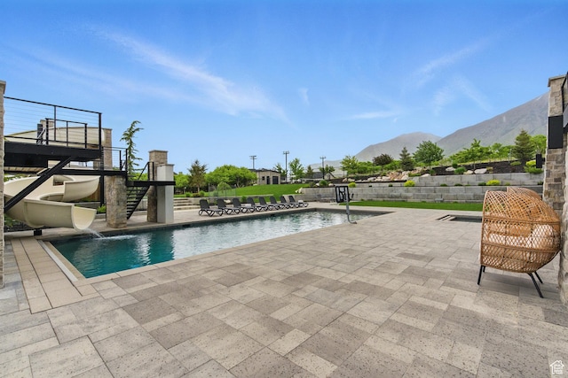 view of swimming pool with stairway, a patio, and a mountain view