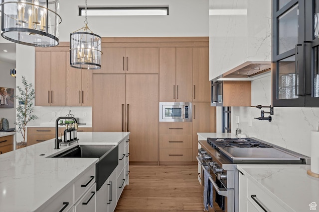 kitchen with stainless steel appliances, a sink, light wood-style flooring, and light brown cabinetry