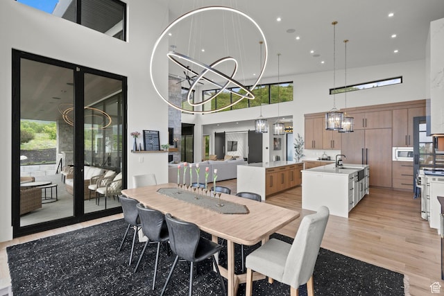 dining area with a high ceiling, a chandelier, light wood-style floors, and recessed lighting