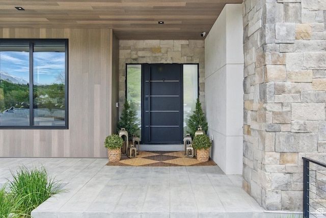 doorway to property featuring stone siding and a surveillance system