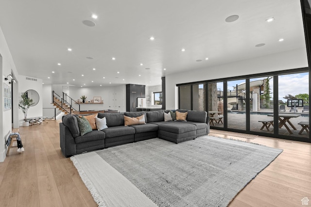 living area featuring recessed lighting, healthy amount of natural light, stairway, and light wood finished floors