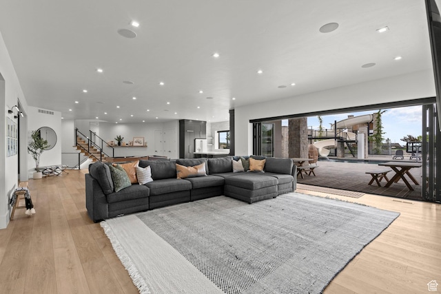 living area featuring recessed lighting, stairway, and light wood-style flooring