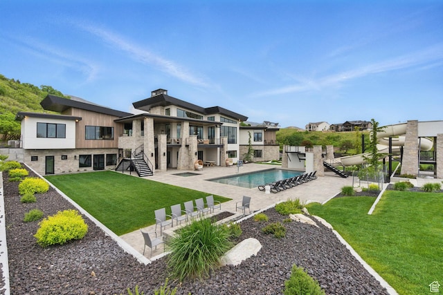outdoor pool featuring stairs, a yard, and a patio area