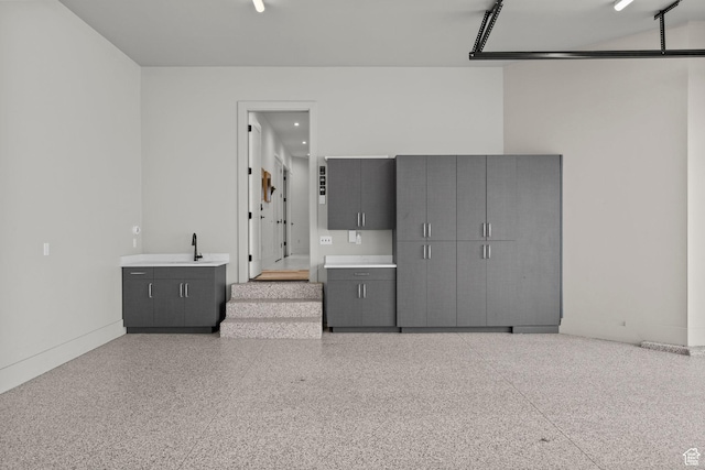 unfurnished bedroom with speckle patterned floor, baseboards, and a sink
