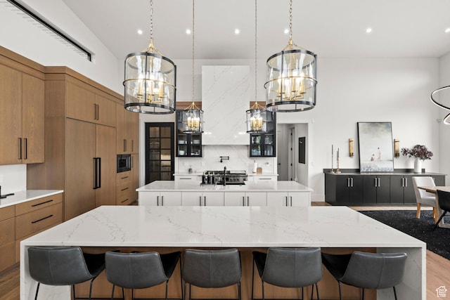 kitchen featuring a large island, a chandelier, brown cabinets, built in appliances, and a high ceiling