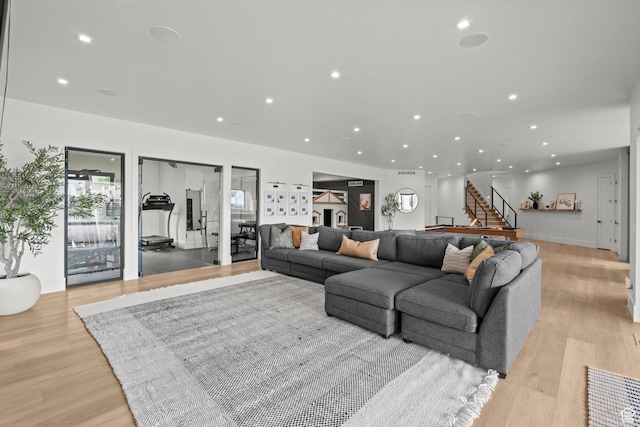 living room featuring light wood-style flooring, recessed lighting, and stairway