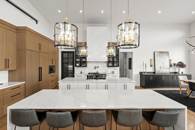 kitchen featuring a large island, a chandelier, built in appliances, brown cabinetry, and recessed lighting