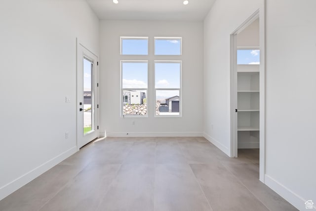 unfurnished room with finished concrete flooring, baseboards, and recessed lighting