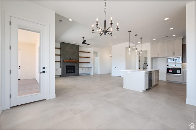 kitchen featuring appliances with stainless steel finishes, a chandelier, a sink, a fireplace, and hanging light fixtures