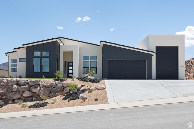 contemporary home featuring an attached garage, concrete driveway, board and batten siding, and stucco siding