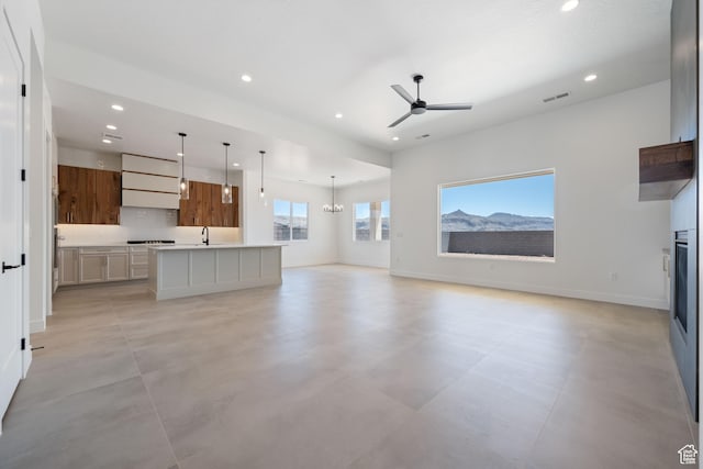 unfurnished living room with recessed lighting, a ceiling fan, baseboards, a chandelier, and a glass covered fireplace