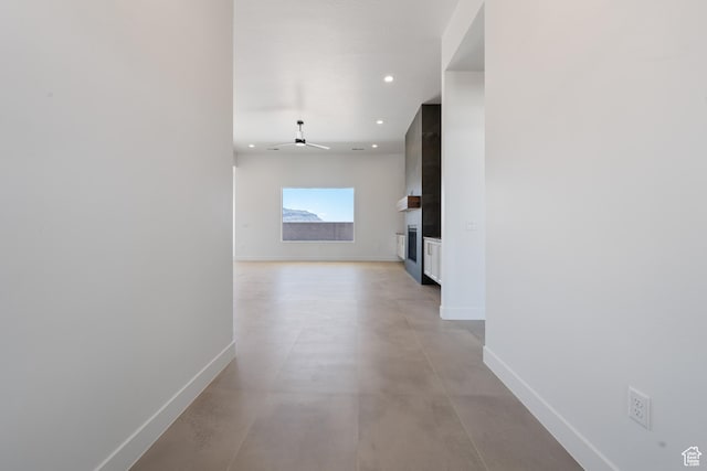 hallway with baseboards, concrete flooring, and recessed lighting