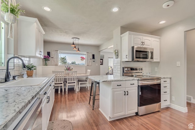 120 N 5th St, Tooele, UT 84074 - kitchen featuring stainless steel appliances, a sink, light wood-style flooring, white cabinetry, and recessed lighting