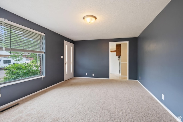 carpeted spare room featuring baseboards and a textured ceiling