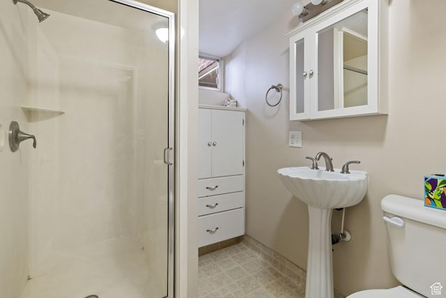 bathroom with a shower stall, toilet, and baseboards