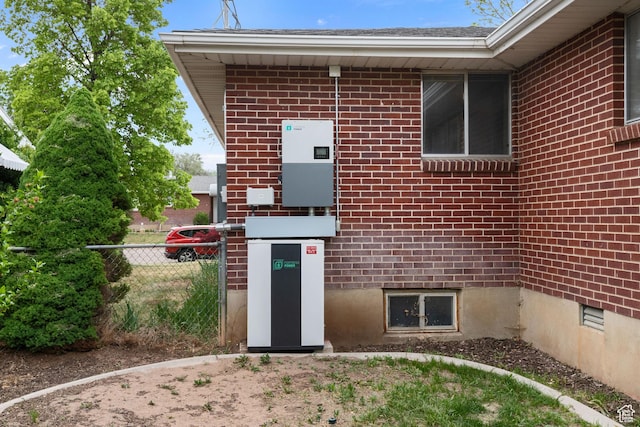 view of exterior entry featuring fence and brick siding