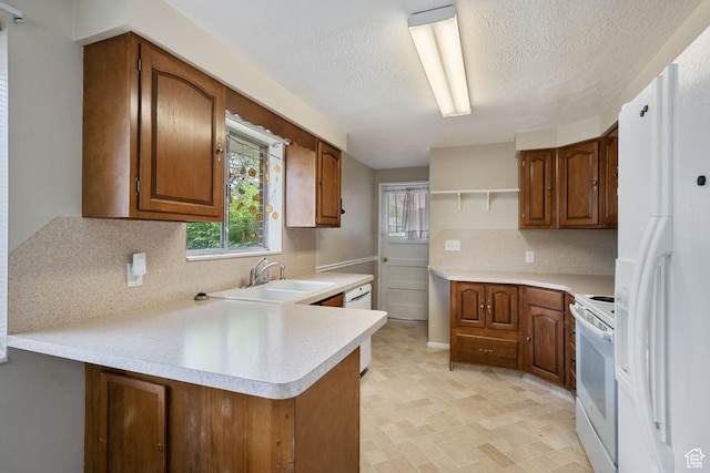 kitchen with white appliances, a sink, a peninsula, decorative backsplash, and light countertops
