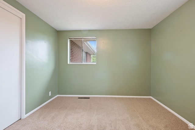 unfurnished room with carpet flooring, baseboards, and a textured ceiling