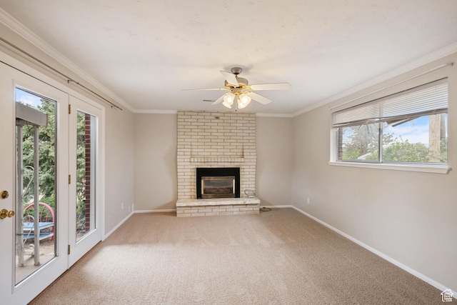 unfurnished living room featuring ceiling fan, carpet floors, baseboards, a brick fireplace, and crown molding