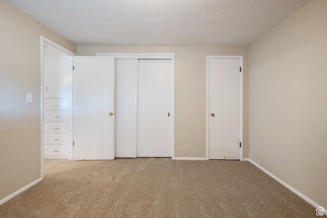 unfurnished bedroom with carpet floors, baseboards, a closet, and a textured ceiling