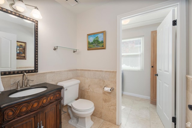 half bath featuring toilet, tile walls, vanity, wainscoting, and tile patterned floors