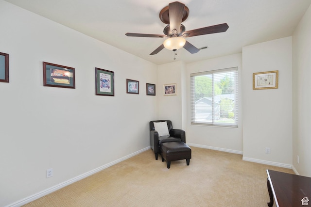 sitting room with a ceiling fan, light colored carpet, and baseboards