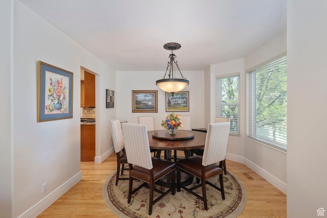 dining area with light wood-type flooring and baseboards