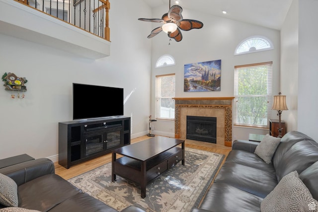 living area featuring a ceiling fan, high vaulted ceiling, healthy amount of natural light, wood finished floors, and baseboards