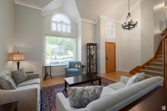 living area featuring high vaulted ceiling, a chandelier, stairway, wood finished floors, and baseboards