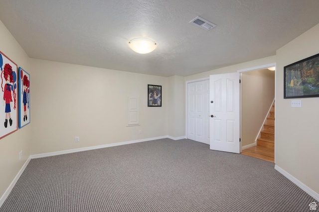carpeted empty room with baseboards and a textured ceiling