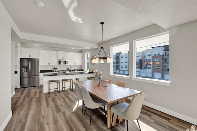 dining area featuring baseboards, wood finished floors, a textured ceiling, and a chandelier