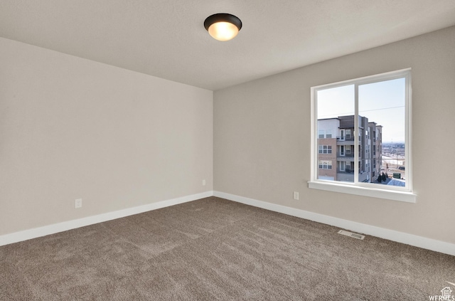 carpeted spare room featuring baseboards