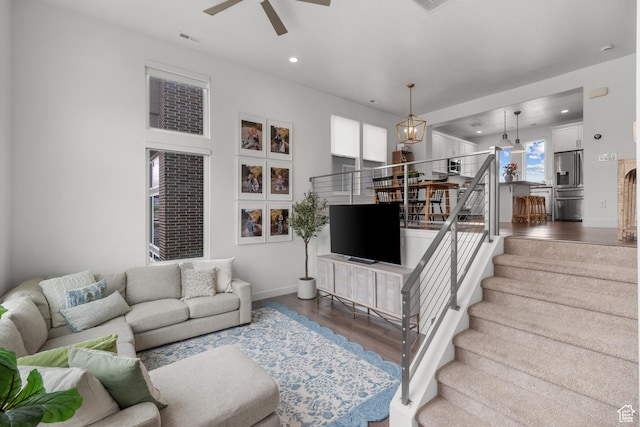 living area featuring wood finished floors, ceiling fan, a chandelier, stairs, and recessed lighting