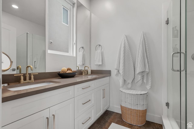 full bathroom with a stall shower, double vanity, wood finished floors, and baseboards
