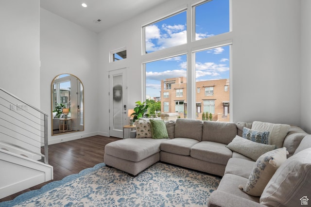living room with a high ceiling, wood finished floors, stairs, baseboards, and recessed lighting