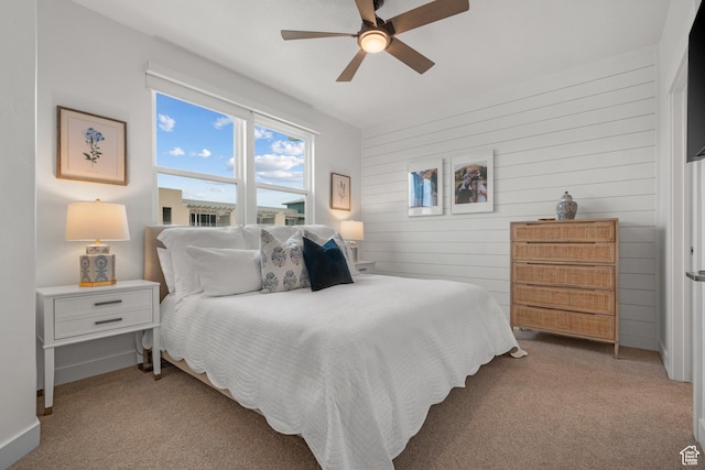 carpeted bedroom featuring wooden walls, a ceiling fan, and baseboards