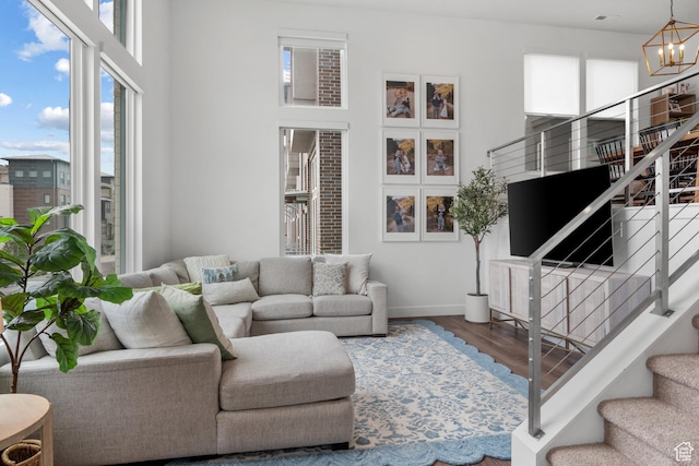 living area featuring stairway, baseboards, a chandelier, wood finished floors, and a high ceiling