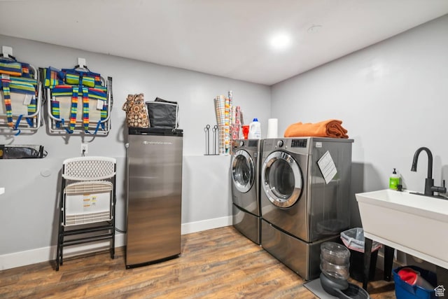 laundry room with washer and dryer, wood finished floors, and baseboards