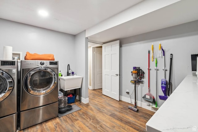 washroom with wood finished floors, washing machine and clothes dryer, and baseboards