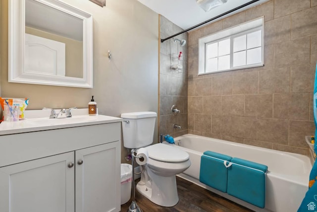 full bathroom with wood finished floors, toilet, vanity, and washtub / shower combination